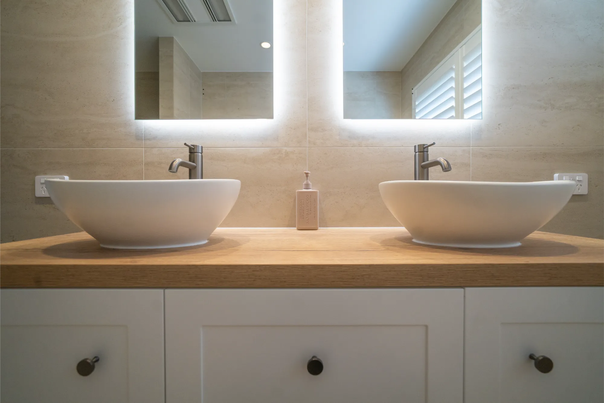 Double vanity with backlit mirrors and vessel sinks